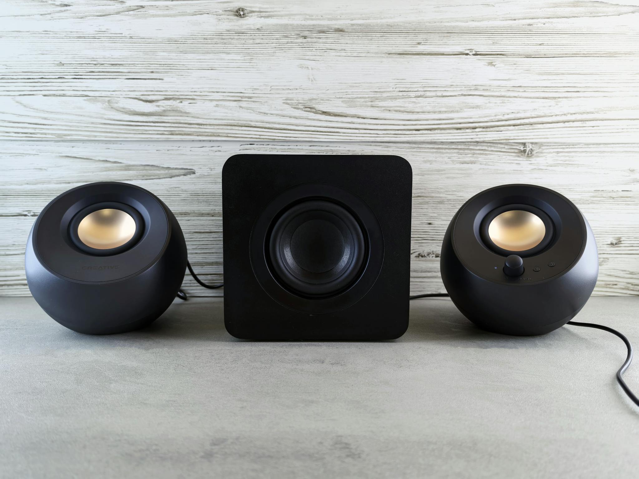 Black spherical speakers and subwoofer arranged on a stylish textured surface, perfect for a music-themed setting.